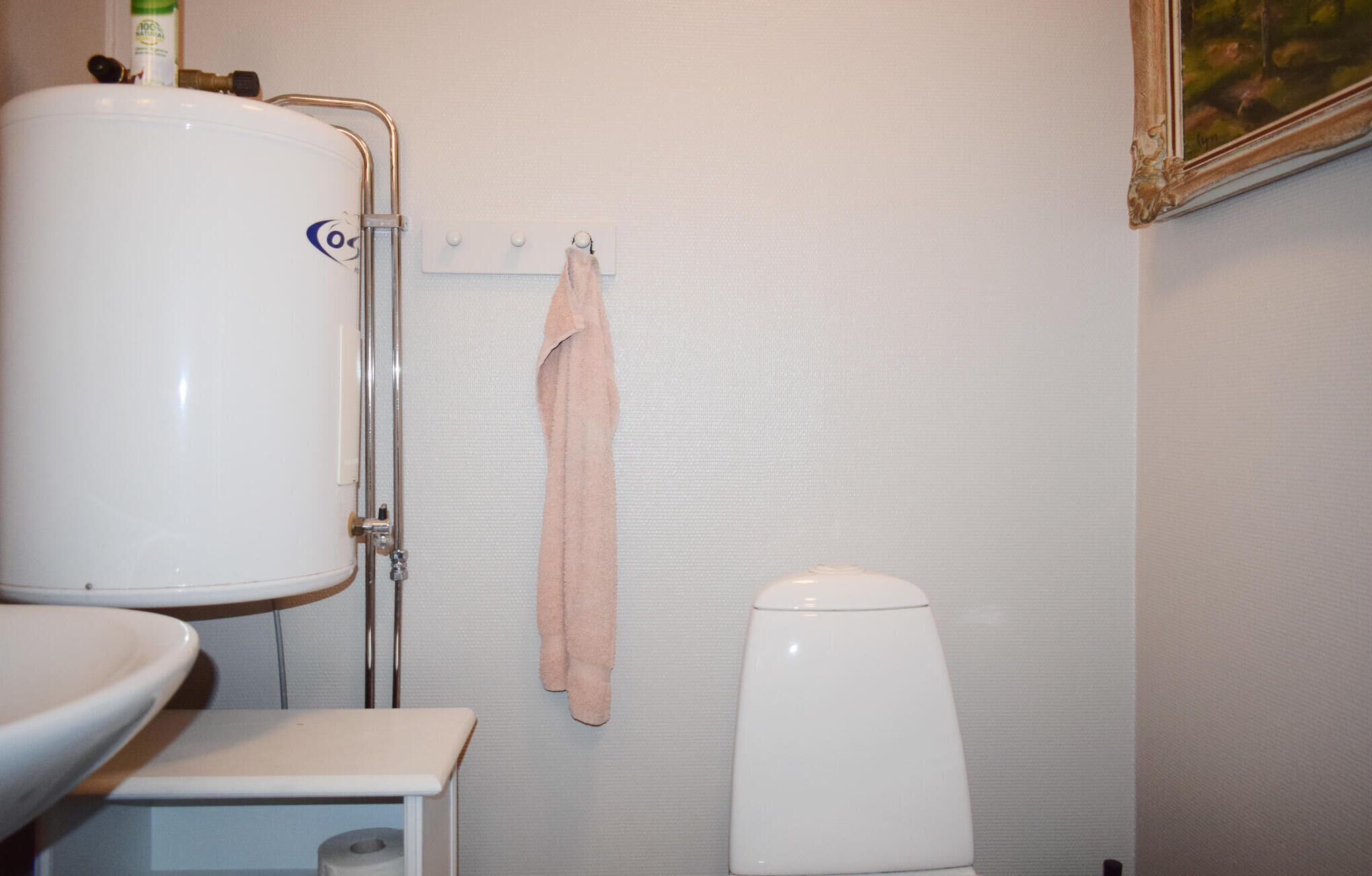 A bathroom with a white toilet, a white sink, and a large white water tank.