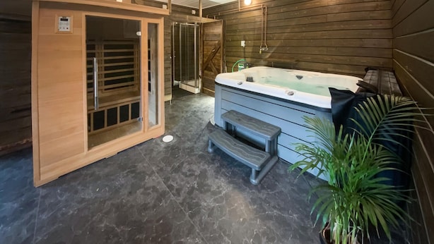A spa area with a hot tub, wooden walls, and a potted plant. - Beautiful home in Reftele with WiFi (Reftele)