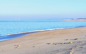 A beach with clear blue water, pebbles, and a distant lighthouse. - 3 bedroom stunning home in Gonneville-le-Theil (Gonneville-le-Theil)