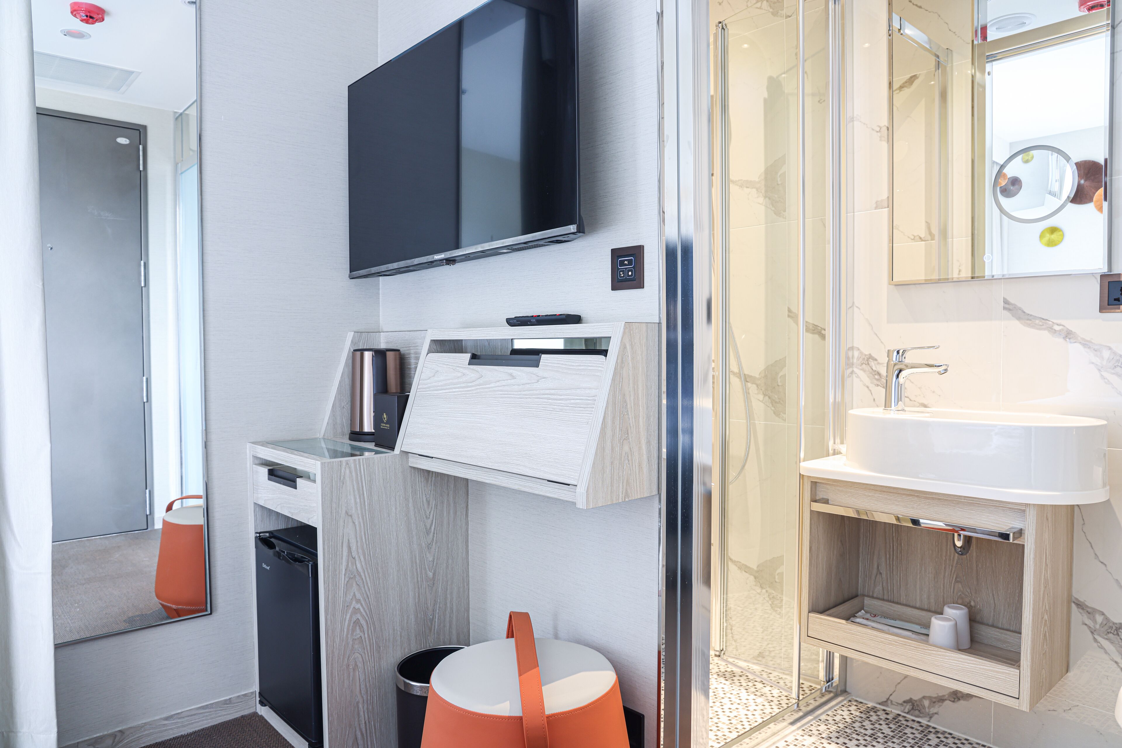 Une salle de bain moderne équipée d’un téléviseur encastré, d’un lavabo et d’un miroir.