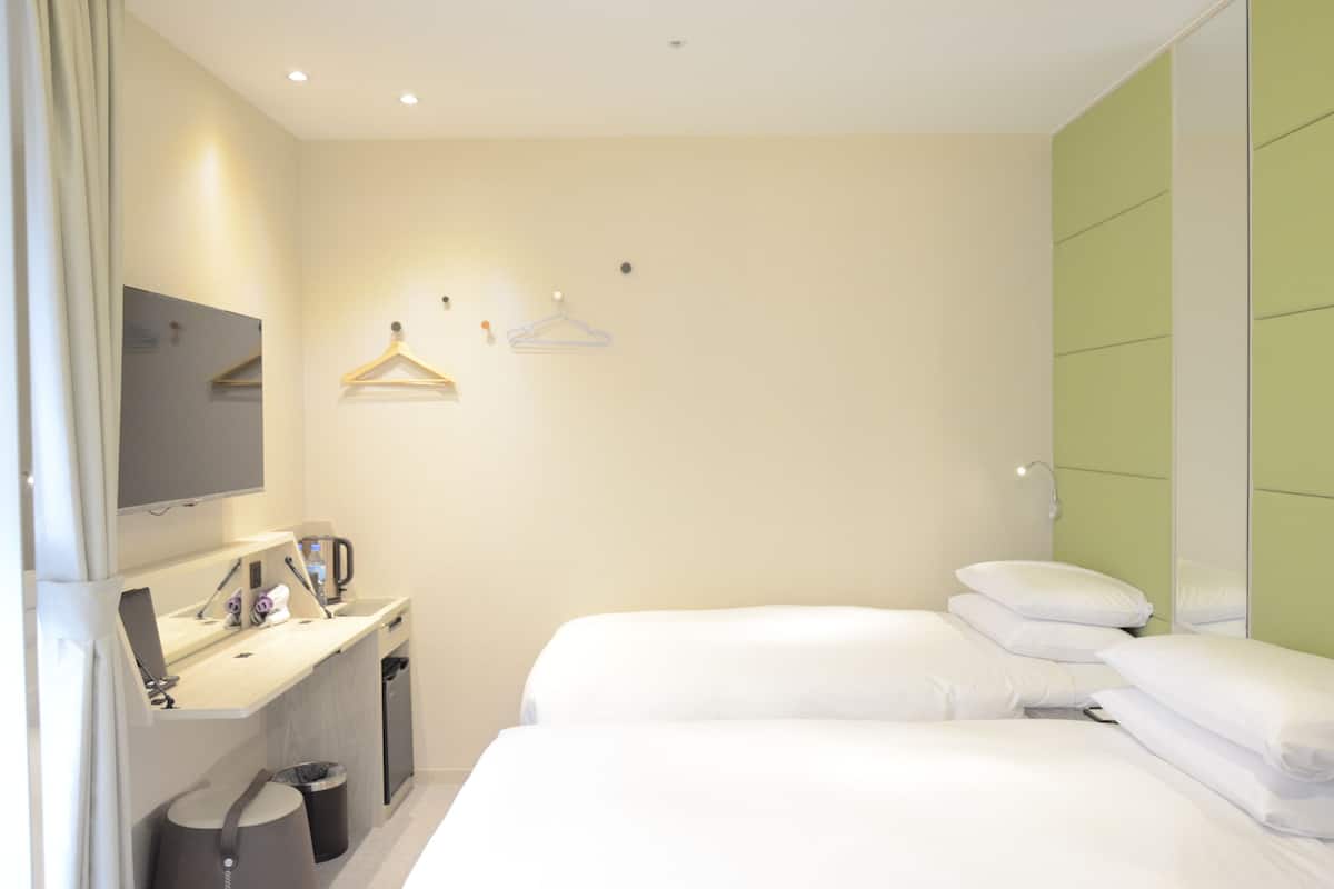 Een hotelkamer met een bed, een bureau met een computer, een spiegel en een tv aan de muur.