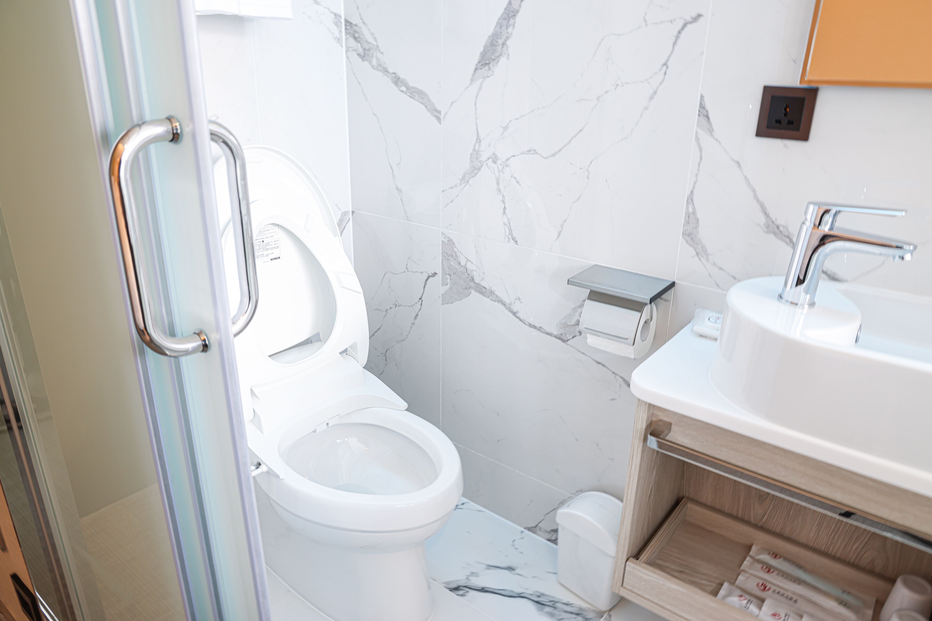 A modern bathroom with a toilet, sink, and marble walls.