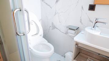 A modern bathroom with a toilet, sink, and marble walls.