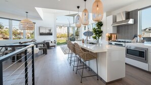 A modern kitchen with a central island, bar stools, and pendant lighting.