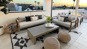 A modern living room with a sofa set, a coffee table, and a view of the cityscape at sunset.