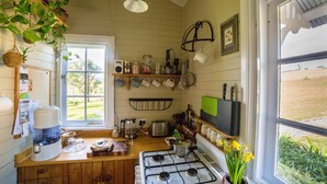 Een keuken met een gasfornuis, een waterdispenser en diverse keukengerei op planken.