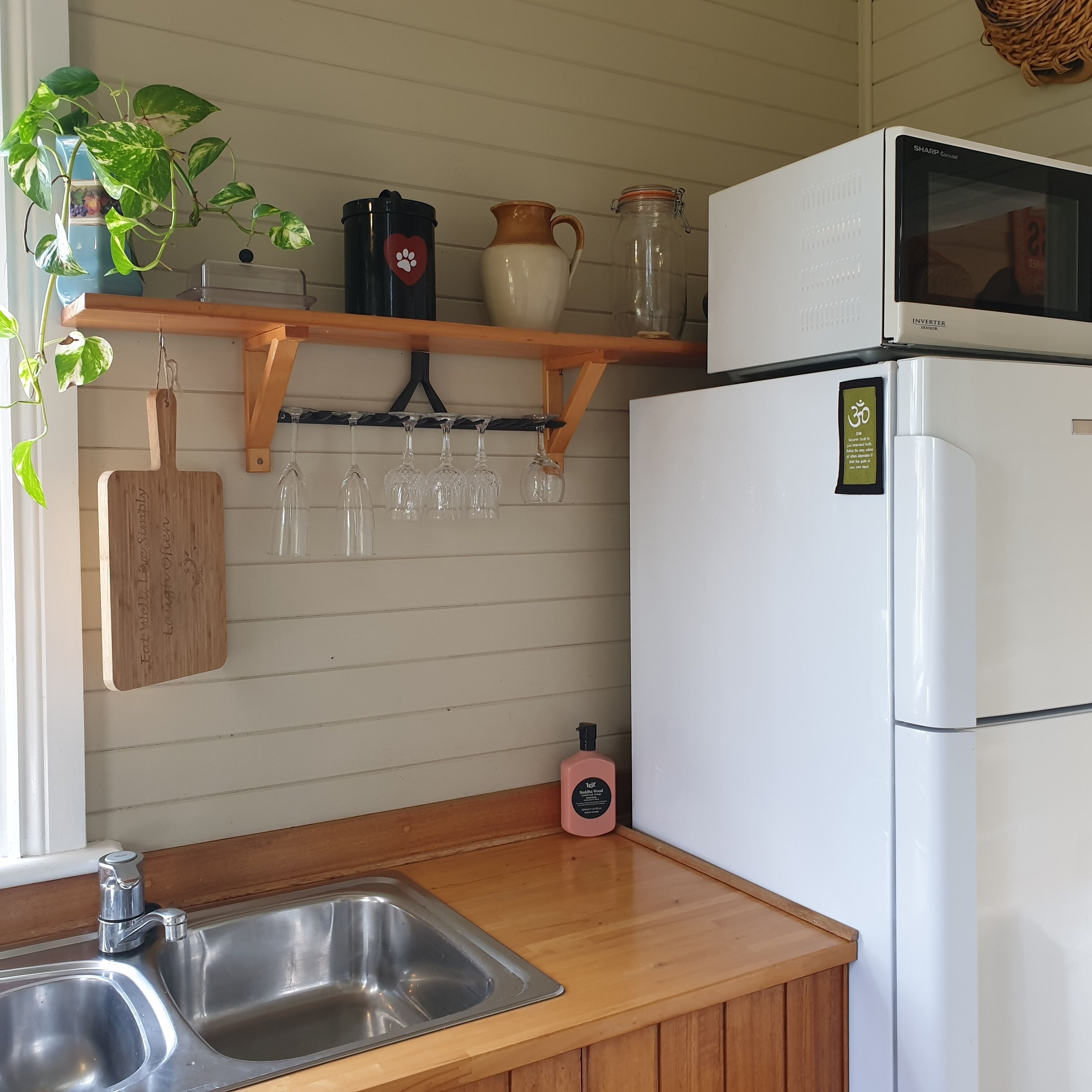 A kitchen with a stainless steel sink, wooden countertop, and a white refrigerator.