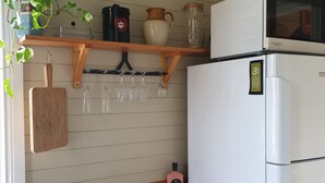 Een keuken met een roestvrijstalen spoelbak, een houten aanrechtblad en een witte koelkast.