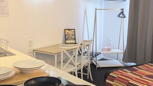 Une chambre d’hôtel compacte comprenant un coin cuisine, un espace repas, un lit et un téléviseur fixé au mur.