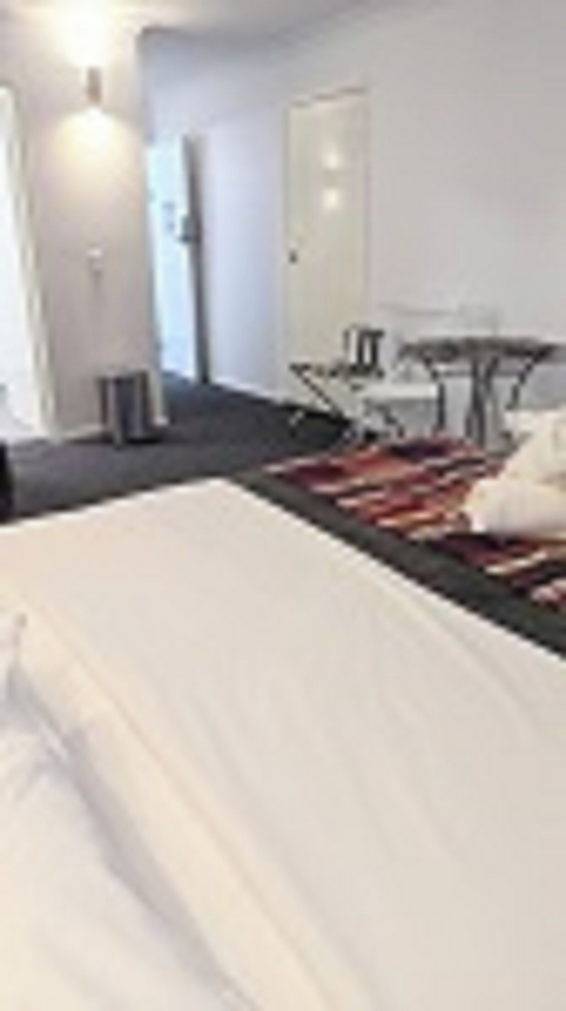 A hotel room with a bed, a desk, and a chair.