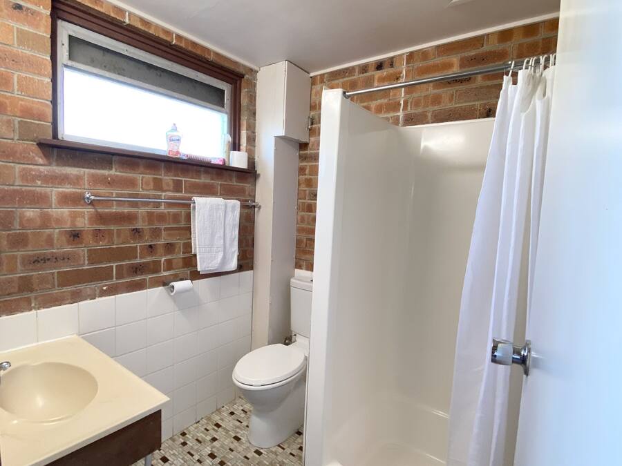 Une salle de bain avec des toilettes, un lavabo et une douche.