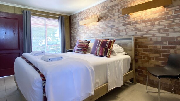 Une chambre avec un mur en briques, un lit en bois et une chaise.