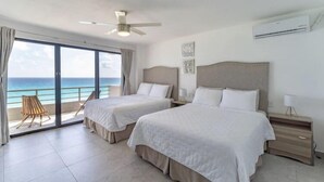 Ein Hotelzimmer mit zwei Betten, einem Deckenventilator, einer Klimaanlage und einem Balkon mit Meerblick.