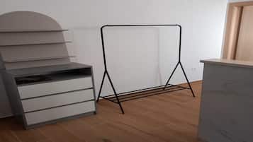Una habitación con piso de madera, un gabinete gris con cajones y un estante metálico negro contra la pared.