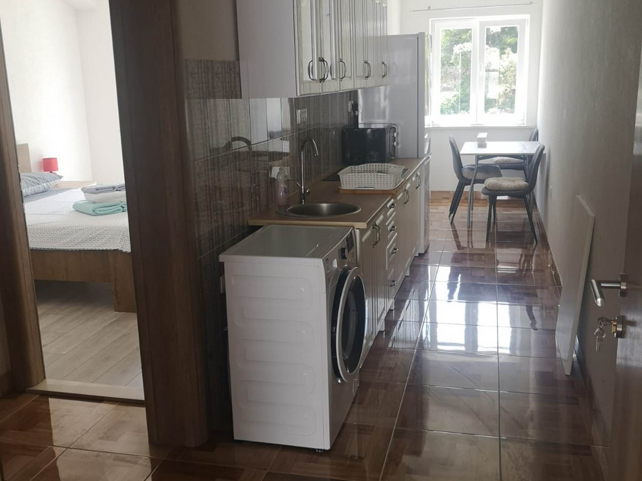 Une cuisine de taille réduite, équipée d’un lave-linge, d’un évier et de placards.