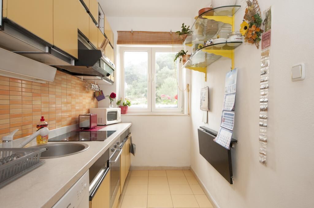A compact kitchen with a window, a microwave, a toaster, and a sink.
