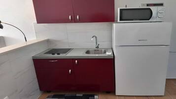 Una cocina compacta con microondas, lavaplatos y refrigerador.