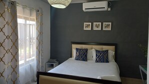 Un dormitorio con cama, aire acondicionado, una mesita de noche y un equipo de aire acondicionado de pared.
