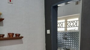 Una cocina con pared blanca con textura, un estante de madera con cuencos y un armario rojo.