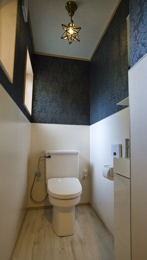 A small, modern bathroom with a toilet, shower, and a decorative star-shaped light fixture.