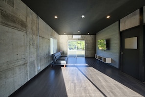 A modern interior with a concrete wall, a bench, and a door.