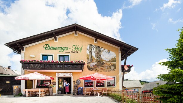 A building with a sign reading "Braunegger-Hof Familie MAYER" and outdoor seating with umbrellas. - Brauneggerhof Gasthof Mayer (Raxendorf)