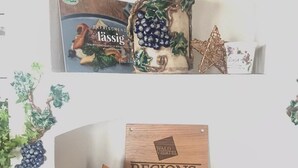 A shelf with a book titled 'ERFRISCHEND' and a decorative item with grapes and leaves. Below, there's a wooden sign with 'REGIONS- PARTNER' and a reindeer decoration. - Brauneggerhof Gasthof Mayer (Raxendorf)