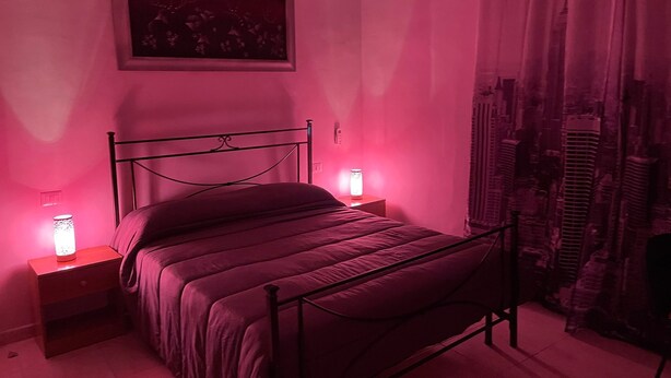 A bedroom with a bed, nightstands, a wall-mounted picture, and a window with curtains. - STATION'S ROOM (AVELLINO)