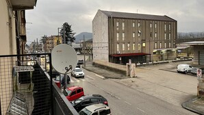 A street view with parked cars, a large building with a red roof, and a satellite dish on a balcony. - STATION'S ROOM (AVELLINO)