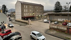 A multi-story building with a flat roof and large windows, surrounded by parked cars and a street. - STATION'S ROOM (AVELLINO)