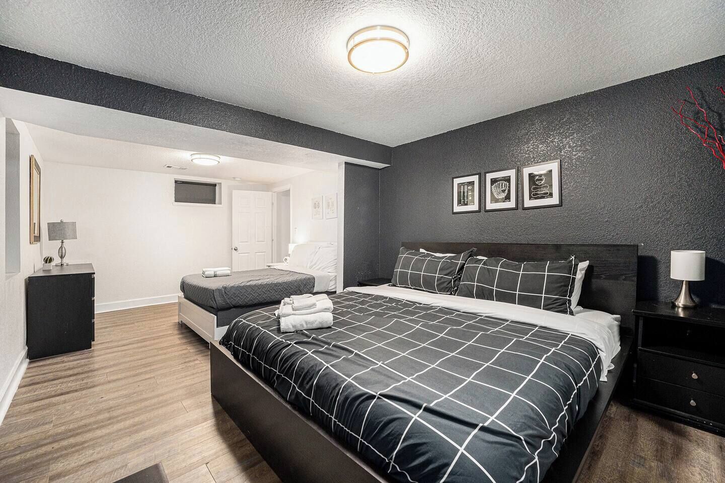 Une chambre moderne avec un grand lit, une table de chevet, une commode et un téléviseur fixé au mur.