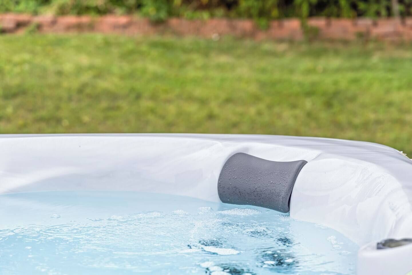 A hot tub with water, surrounded by a grassy area.