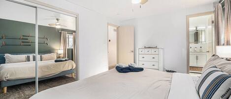 A modern hotel room with a large bed, a wardrobe, a dresser, and a ceiling fan.