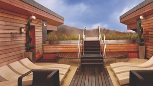 A sauna area with wooden walls, a central staircase, and lounge chairs. - Luxury Loch Lomond Lodge (Alexandria)