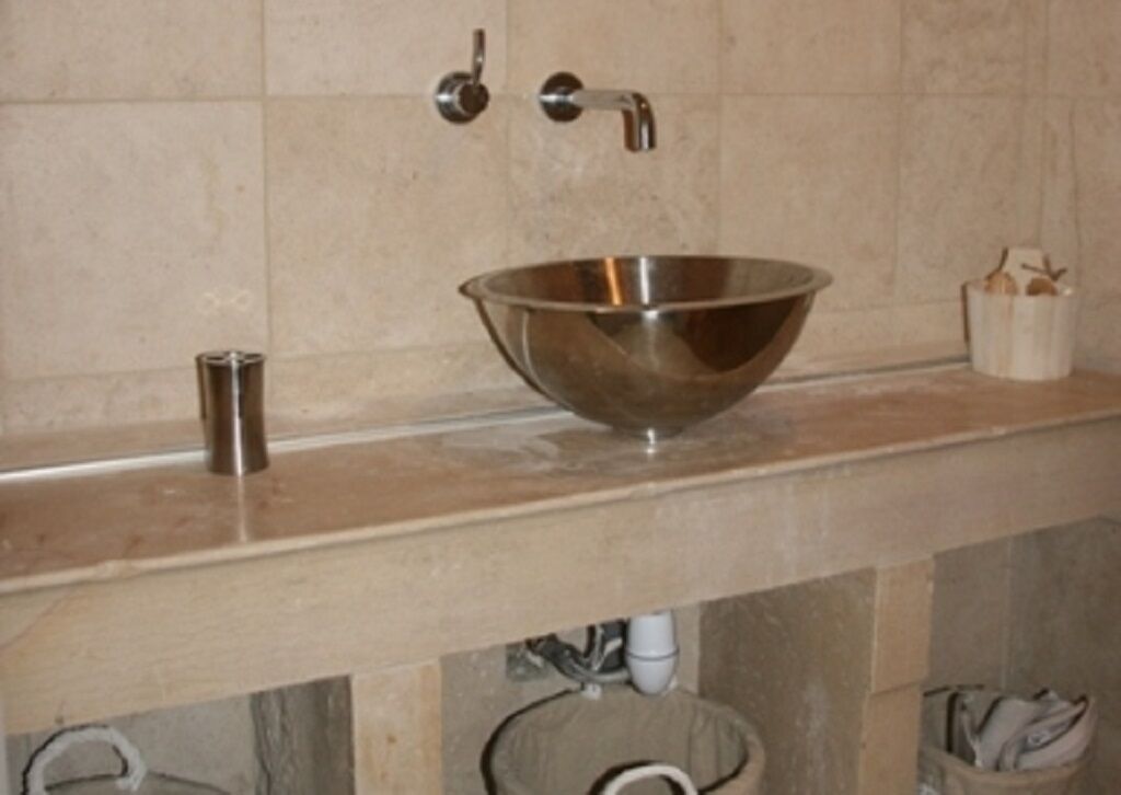 A bathroom with a metallic bowl sink, a faucet, and a small container with a toothbrush.
