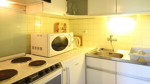 Une cuisine de taille réduite équipée d’un four à micro-ondes, d’une cuisinière et d’un évier.