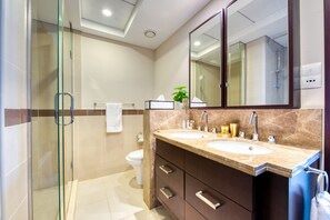 Une salle de bain moderne avec deux lavabos, une douche à l’italienne en verre et un grand miroir.