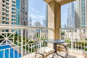 Un balcon avec une piscine, une balustrade blanche et une table avec des chaises.