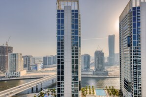 Un edifici alt amb un disseny arquitectònic modern, amb una estructura vertical destacada i una zona de piscina al terrat.