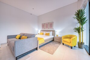 Une chambre moderne avec un lit, un canapé, un fauteuil et une plante en pot.