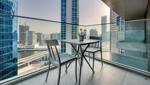 Ein moderner Balkon mit Glasgeländer, zwei Stühlen und einem Tisch mit einer Topfpflanze.