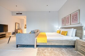 A modern bedroom with a bed, bedside tables, a TV, and artwork on the wall.