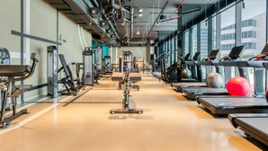 Ein Fitnessstudio mit Laufbändern, Kraftgeräten und Trainingsbällen.