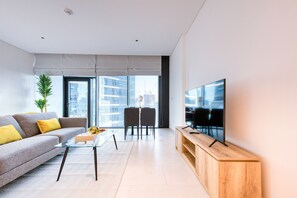Un salon moderne avec un canapé, une table basse et un téléviseur posé sur un meuble en bois.