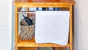 Un baño con tocador de madera, un espejo redondo, un lavabo negro y una toalla en el estante.