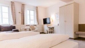 Une chambre d’hôtel avec deux lits, un bureau, une chaise, une télévision et une armoire.
