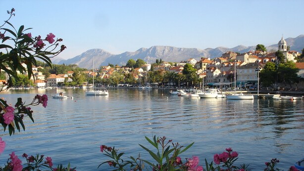 Blick auf das Wasser mit Booten, einer Kirche und Bergen im Hintergrund.