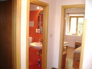 Ein Badezimmer mit Waschbecken, Spiegel und roten Fliesen.