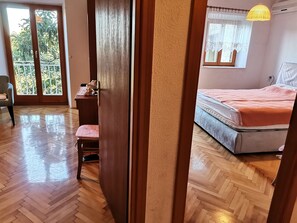 Ein Schlafzimmer mit Bett, Stuhl, Schreibtisch und einem Fenster mit Blick auf Bäume.