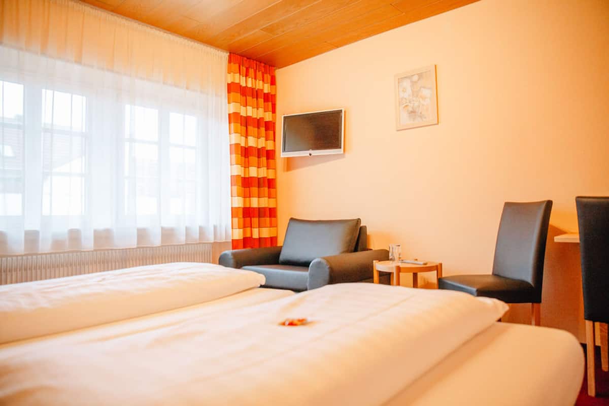 Une chambre d’hôtel avec deux lits, une télévision, une chaise et une petite table.